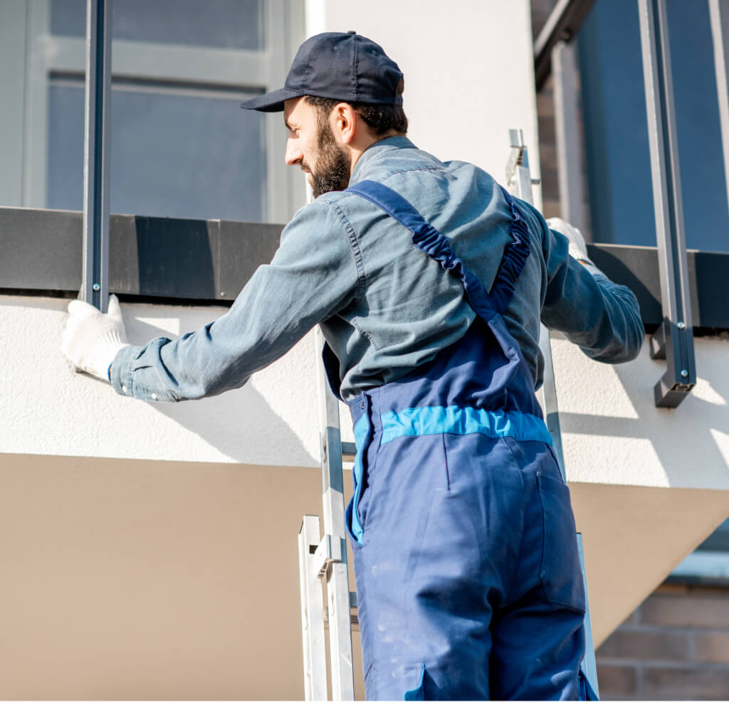 Tradesman in blue overalls fitting metal railing posts on a balcony